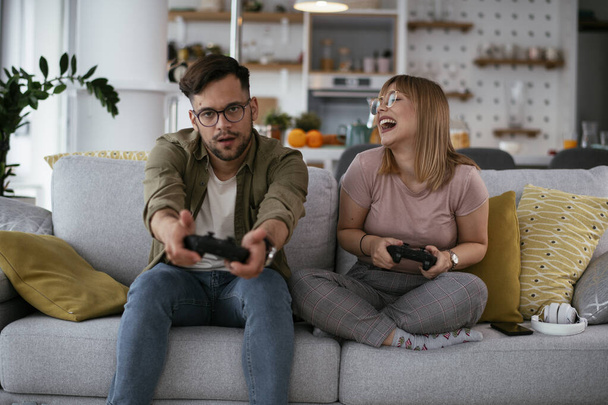 Beautiful young couple playing video games at home. - Photo, Image