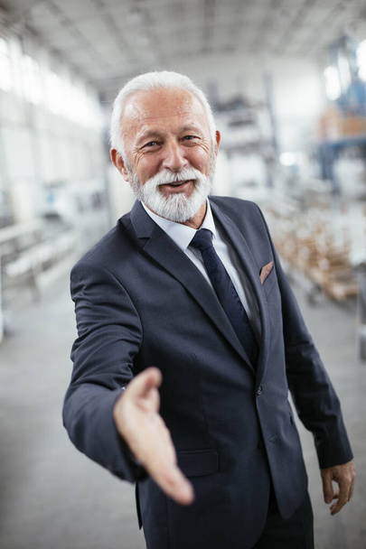 Portrait of handsome senior businessman. Man handshake in factory. - Photo, Image