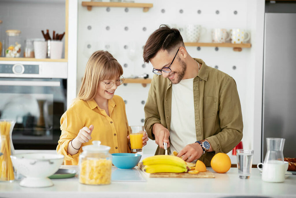 若い夫婦が家で朝食を作っている。キッチンで楽しい時間を過ごすカップル. - 写真・画像