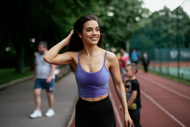 Beautiful woman training on running track. Young woman in blue sportswear - Photo, Image
