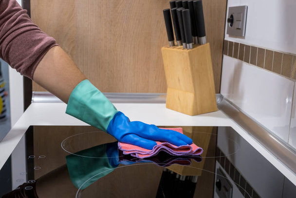 Evdeki masayı temizlemek mutfak masasının yüzeyini dezenfektan sprey şişesiyle sterilize etmek, yüzeyi eldivenlerle yıkamak. COVID-19 içeriden temizleme. - Fotoğraf, Görsel