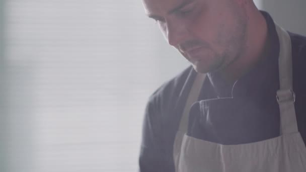 Tilt down close-up shot van mannelijke chef-kok zout warm eten in koekenpan tijdens het koken op fornuis in de keuken - Video