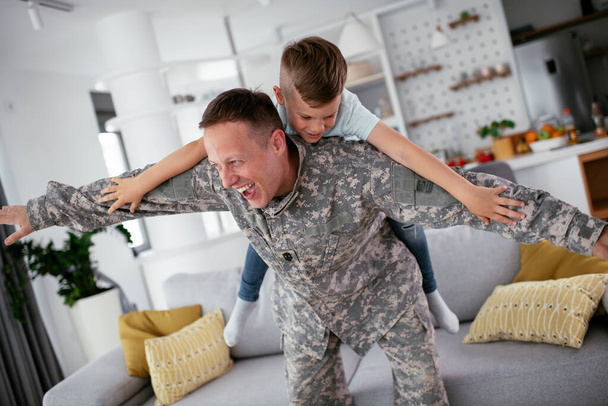 военный играет с сыном дома  - Фото, изображение