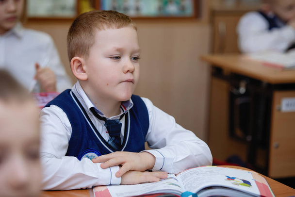 Schoolboy at a desk in the classroom during the lesson. School primary education. Selective focus. - 写真・画像