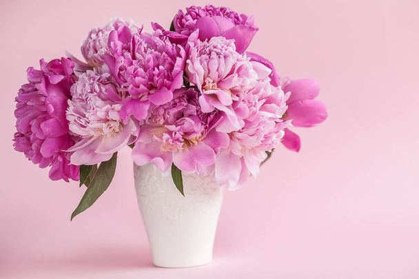roze pioenrozen in een vaas op een witte achtergrond - Foto, afbeelding