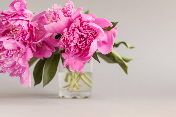 木のテーブルの上の花瓶にピンクの牡丹の花束 - 写真・画像