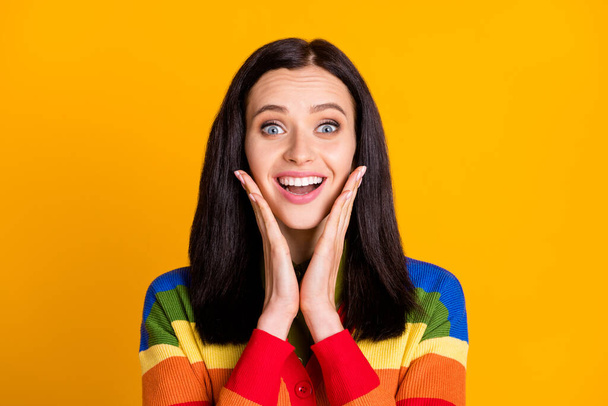 Photo of happy surprised young woman excited amazed news information hands touch cheeks isolated over yellow color background - Zdjęcie, obraz