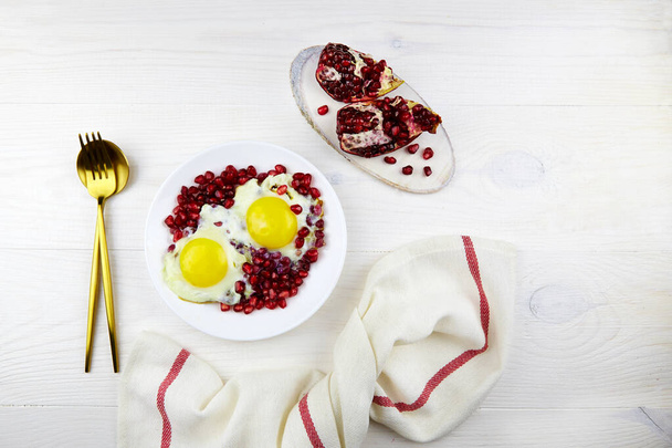 Narnumru (Nar numru) or pomegranate with egg on plate on white wooden background. Traditional Azerbaijan dish. - Foto, Imagen