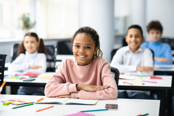 Porträt eines kleinen schwarzen Mädchens am Schreibtisch im Klassenzimmer - Foto, Bild