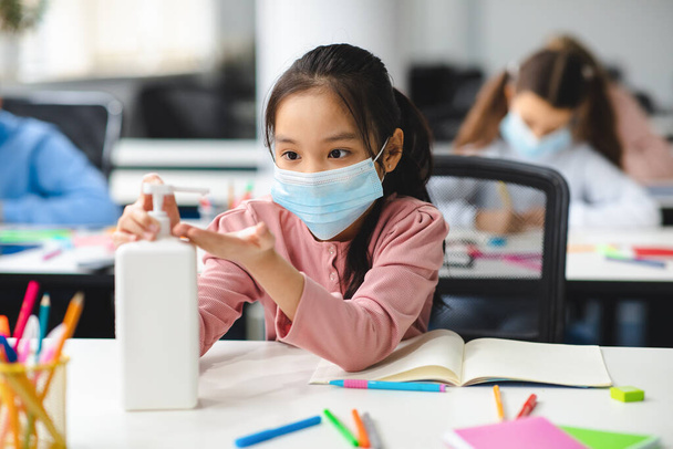 Aasian tyttö soveltamalla antibakteerinen puhdistusaine käsissä - Valokuva, kuva