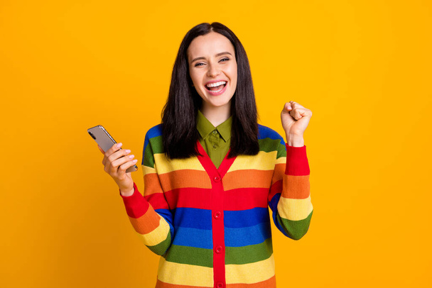 Photo of young smile positive girl happy excited win victory hold cellphone isolated over yellow color background - Foto, Imagem