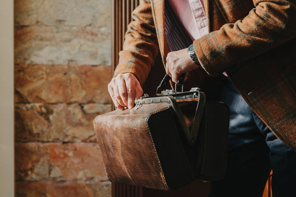 gentleman in a stylish plaid jacket opens a vintage bag in the hous - Photo, Image