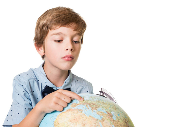 mladý rozkošný chlapec dívá na zeměkouli, izolované na bílém pozadí s prostorem pro text - Fotografie, Obrázek