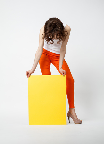 Young woman in orange pants holding yellow paper - Foto, Imagem