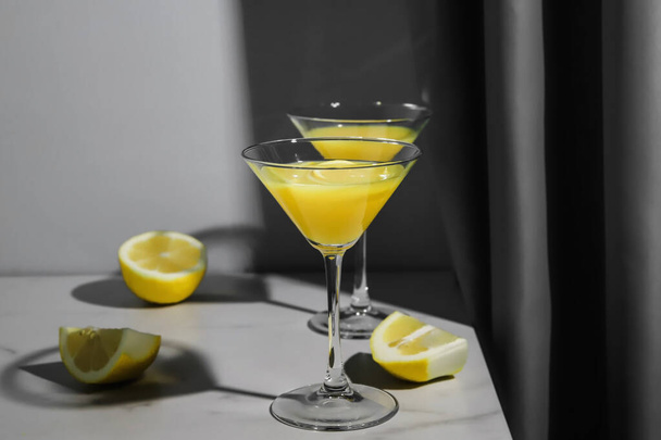 Апельсиновый сок или лимонный спирт в стаканах на мраморном столе. Желтые и серые трехцветные натюрморты 2021 года - Фото, изображение