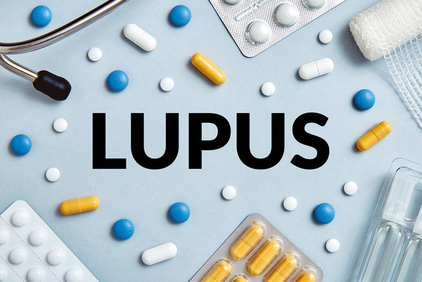 Doença de Lupus, conceito médico cercado por comprimidos e suprimentos médicos em fundo azul. Vista superior - Foto, Imagem