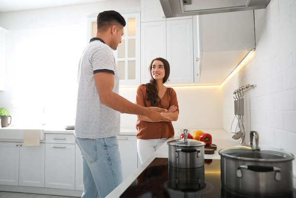 Man and woman talking while cooking in kitchen - Φωτογραφία, εικόνα