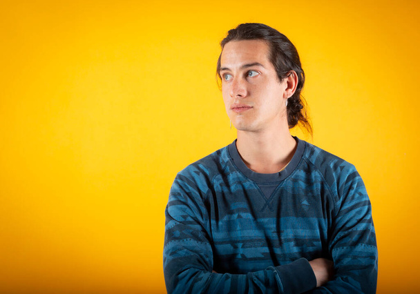 man with blue eyes and casual clothes, looking to the side with crossed arms copy space, on yellow background - Fotoğraf, Görsel