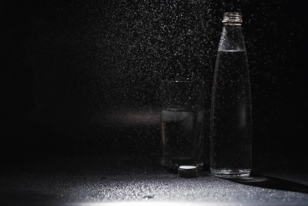 Κοντινό πλάνο ρίχνει καθαρό φρέσκο νερό ποτό από μπουκάλι στο τραπέζι στο σαλόνι. Πόσιμο νερό. Μεταλλικό νερό βιταμινών. Υγιές, πλούσιο σε μεταλλικά στοιχεία, αναζωογονητικό νερό. - Φωτογραφία, εικόνα