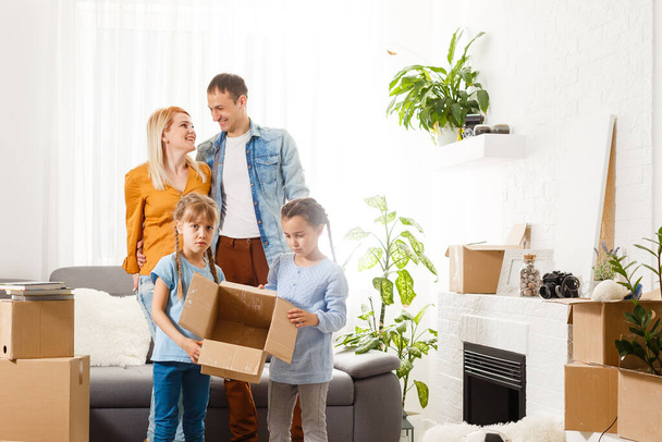Happy family with cardboard boxes in new house at moving day. - Photo, Image
