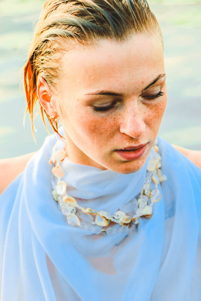 portrait of a beautiful young woman in the water, with freckles and green eyes. beautiful sunset light. athletic body, near the lake, against the background of water - Valokuva, kuva