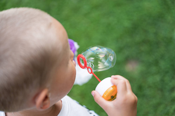Overhead view of a toddler child blowing soap bubbles outside. - Foto, Bild