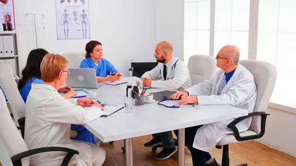 Squadra di medici esperti che tengono un briefing nella sala conferenze dell'ospedale - Foto, immagini