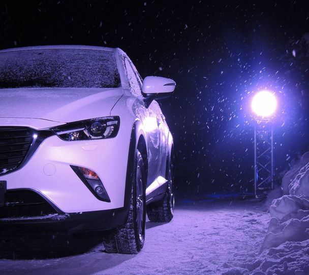 Gecenin kar yağışında spot ışıklarının önünde arabanın farlarını söndür.  - Fotoğraf, Görsel