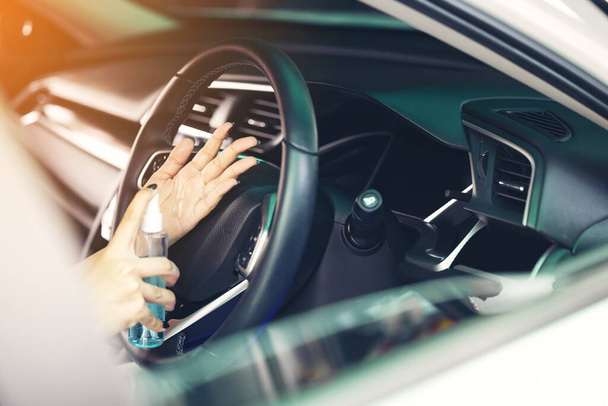 Рука женщины распыляет алкоголь, дезинфицирующий спрей в автомобиле, безопасность, предотвратить инфекцию вируса Ковид 19, коронавирус, загрязнение микробов или бактерии.. - Фото, изображение
