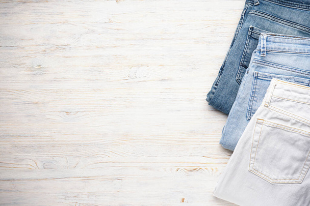 Jeans stacked on a wooden background, flat lay. Place far text. - Zdjęcie, obraz