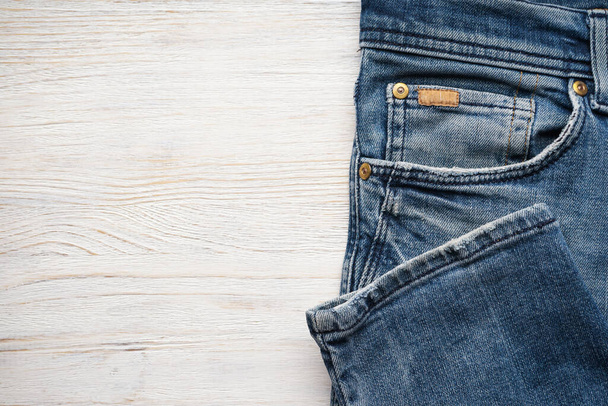 Складные джинсовые штаны на деревянном фоне, место для текста. Плоский лежал. - Фото, изображение