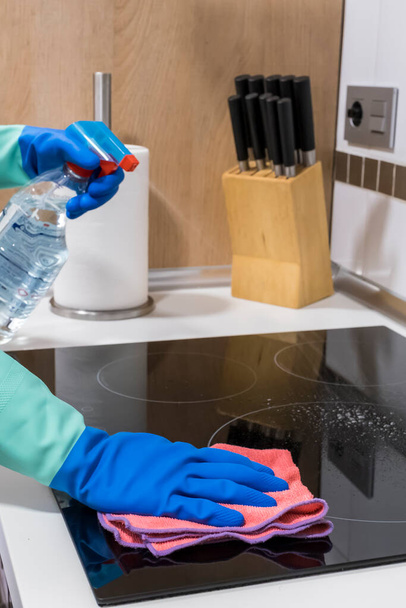 Az asztal tisztítása a házban Fertőtlenítőszer spray palackkal fertőtlenítse a konyhaasztal felületét, mossa le a felületeket kesztyűvel. COVID-19 beltéri fertőtlenítés megelőzése. - Fotó, kép