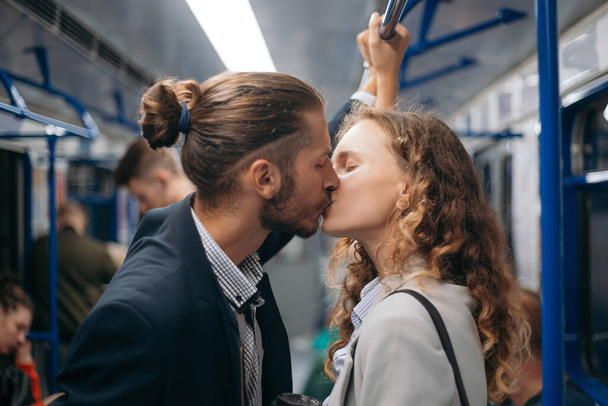 man and a woman in love kiss on a subway train. - Zdjęcie, obraz