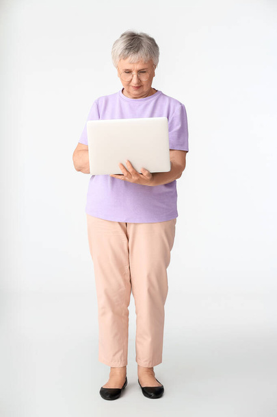 Femme âgée avec ordinateur portable sur fond blanc - Photo, image