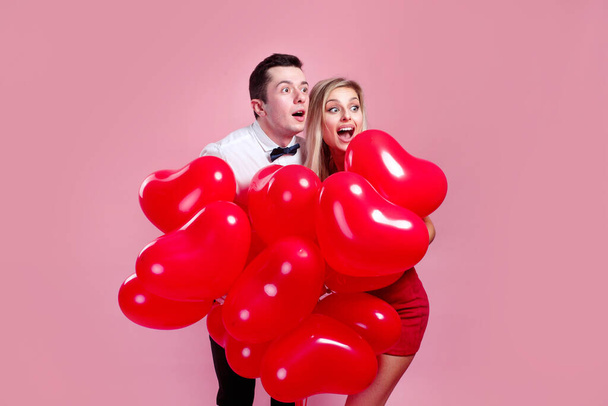 Valentines day. Surprised young couple with balloons heart on pink background - Fotografie, Obrázek