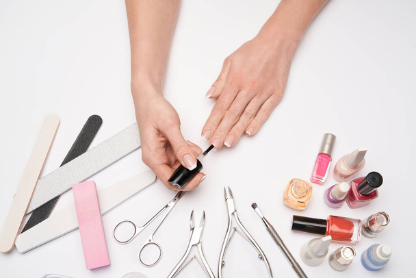 bovenaanzicht van manicure gereedschap set voor nagelverzorging over lichte achtergrond - borstel, schaar, nagellak, bestand en pincet - Foto, afbeelding