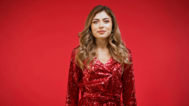 elegant woman in shiny dress looking at camera isolated on red - Photo, Image