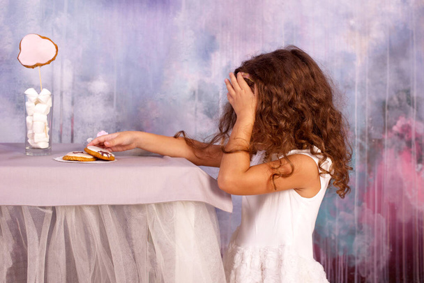 Nieśmiała dziewczyna kradnie ciasteczka ze stołu. Wesołych świąt w pokoju urządzone - Zdjęcie, obraz