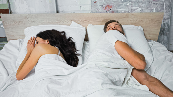 young man looking at brunette woman lying nearby in bed - Photo, Image