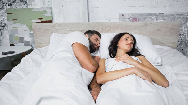 μελαχρινή γυναίκα και γενειοφόρος άντρας κοιμούνται μαζί στο σπίτι - Φωτογραφία, εικόνα
