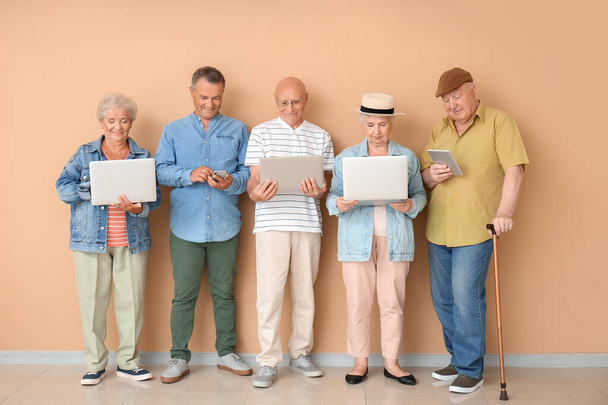 Senior people with different devices near color wall in room - Foto, Bild