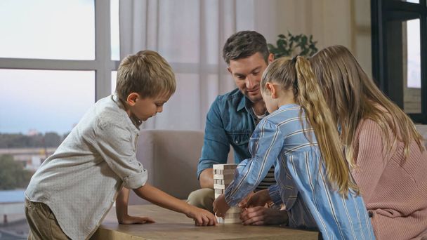 Παιδιά και γονείς που παίζουν ξύλο μπλοκ παιχνίδι στο σπίτι  - Φωτογραφία, εικόνα