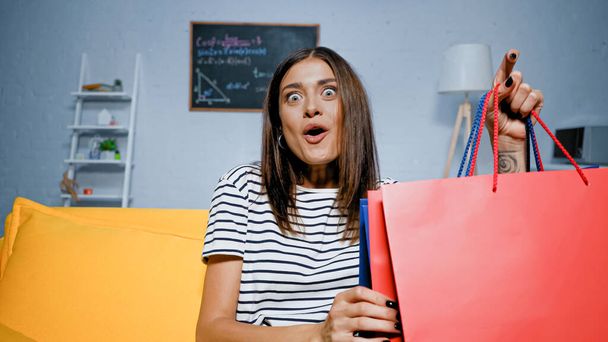 Excited woman holding shopping bags at home  - Photo, Image