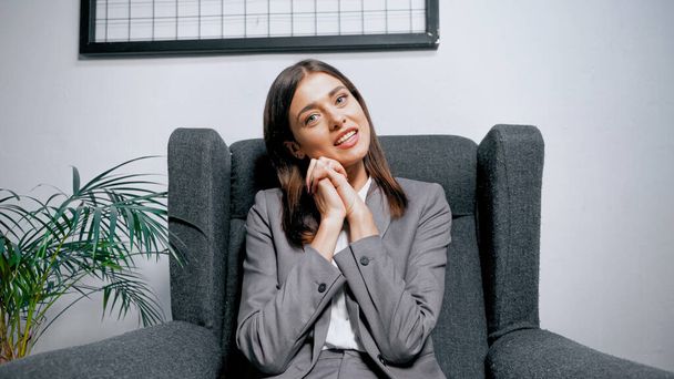 Businesswoman with hands near cheek looking at camera in office  - Foto, immagini