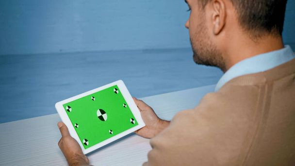 Tabletka cyfrowa z zielonym ekranem w rękach człowieka na niewyraźnym pierwszym planie  - Zdjęcie, obraz