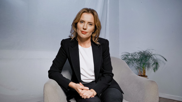 Confident businesswoman sitting on armchair in office  - Foto, afbeelding
