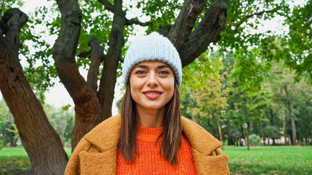Fröhliche Frau in stylischer Kleidung blickt im Herbstpark in die Kamera - Foto, Bild