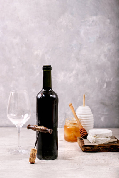 Goat cheese served with honey and bottle of red wine over white texture background. Copy space - Foto, immagini