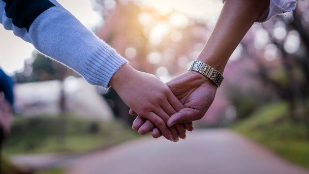 The hand of the young couple holding hands walking forward on the day of love - 写真・画像