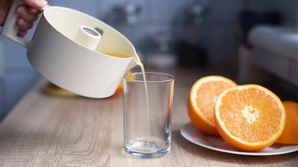 Γυναικείο χέρι χύνει φρέσκο χυμό πορτοκαλιού σε ένα ποτήρι - Πλάνα, βίντεο